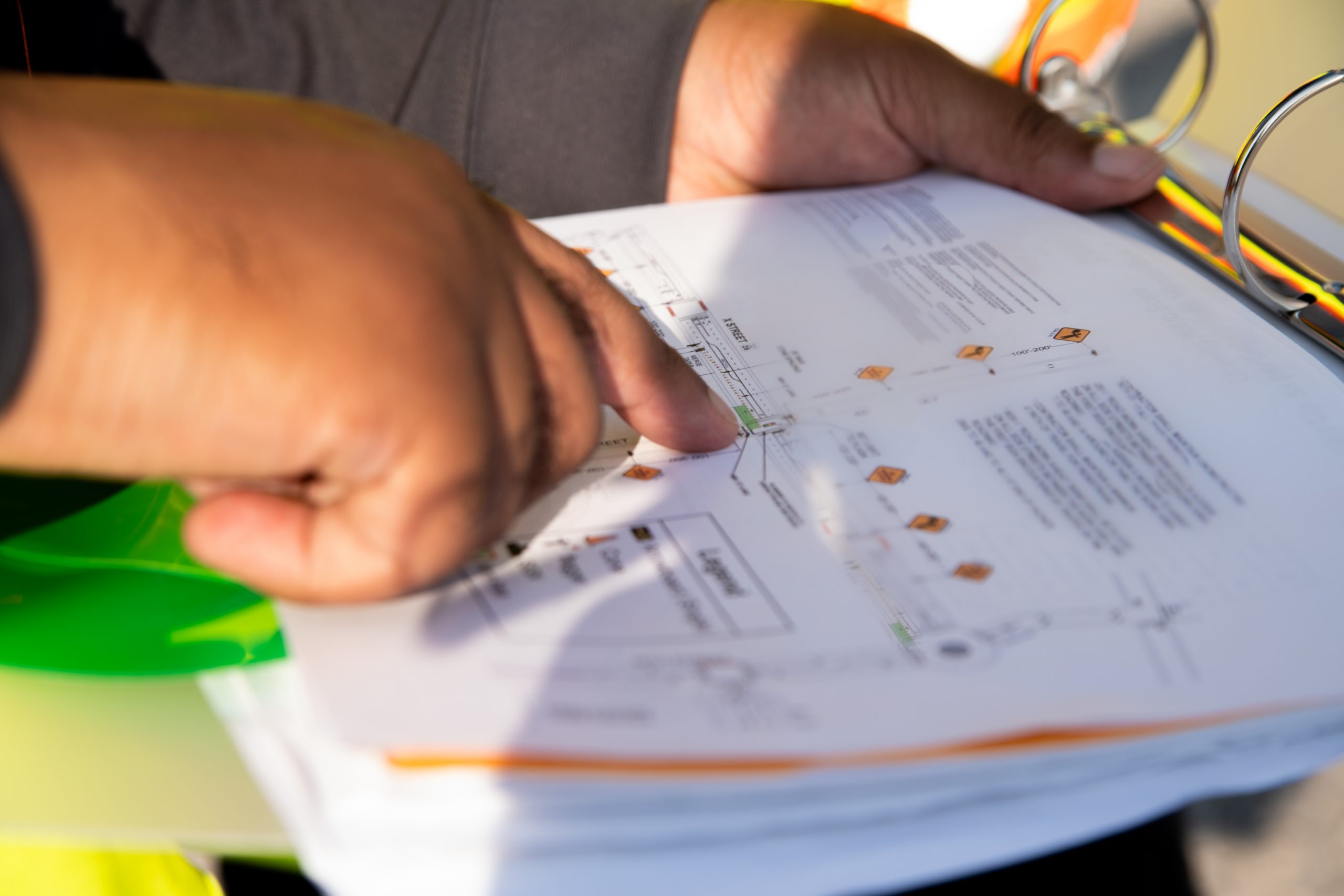 Planer analysiert Verkehrsführungsplan und Bauunterlagen für eine Baustelle