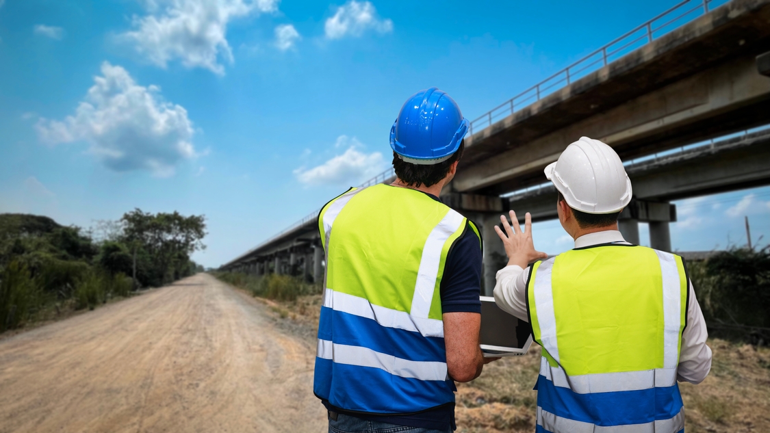 Bauleiter prüfen Verkehrssicherungsmaßnahmen an einer Baustelle